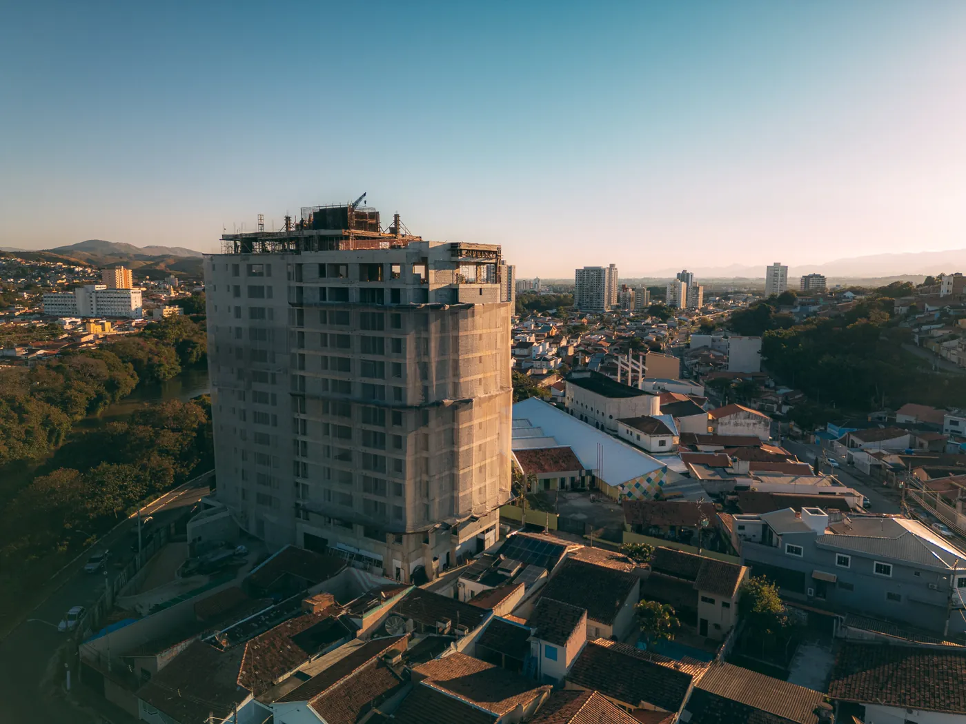 Torre do Ápice em construção ao entardecer, vista em ângulo com a cidade ao fundo
